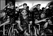 Guatemala City, Guatemala. Wheel chair bound amputee and paraplegic military veterans and their nurses on stage at a military government ceremony to commemorate the military dead and to celebrate the heroes and the end of the civil war.