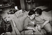 The Innu village of Sheshatshiu, Labrador. Lovers, Cecilia Rich and Germaine Penashue, Sheshatshiu. Behind Germaine’s brother Sylvester is passed out on the floor.

Innu society is not particularly comfortable with overt displays of affection between members of the opposite sex, let alone between same-sex couples, so life for this pair is particularly challenging.

Sylvester Penashue is a member of the lost generation whose parents' identities were solidly formed as traditional hunters and gatherers, and whose children are becoming politicized to fight for their Innu cause. In Sylvester’s case, despite pressures from the Catholic Church and both governments, his parents Pien and Lizette Penashue persisted in taking their children to the country. When Sylvester can get himself to the country he is able to function with purpose, competency and confidence derived from life-long learning .