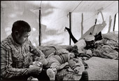 From RETURN TO NITASSINAN/HOMELAND.
Penashue Camp, Mealy Mountains, Nitassinan/Labrador Innu elder, Matthew Penashue dresses his adopted grandson during his morning routine in the country. The Penashues spend several months a year in the bush reclaiming their traditional Innu culture and passing it on to their children and grand-children.