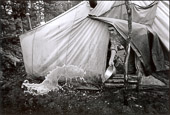 From RETURN TO NITASSINAN/HOMELAND.
Penashue Camp, Melee Mountains. Elder Matthew Penashue discards wash water after doing the breakfast dishes. The Penashues spend several months a year in the bush reclaiming their traditional Innu culture and passing it on to their children and grand-children.