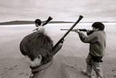 From RETURN TO NITASSINAN/HOMELAND.
Penashue Camp, Lake Minnipi. Innu boys practice hunting on the beach near their campsite. Innu Children learn early to partcipate in family living activities. Girls learn to make and maintain camp; boys to hunt. The Penashues spend several months a year in the bush reclaiming their traditional Innu culture and passing it on to their children and grand-children.